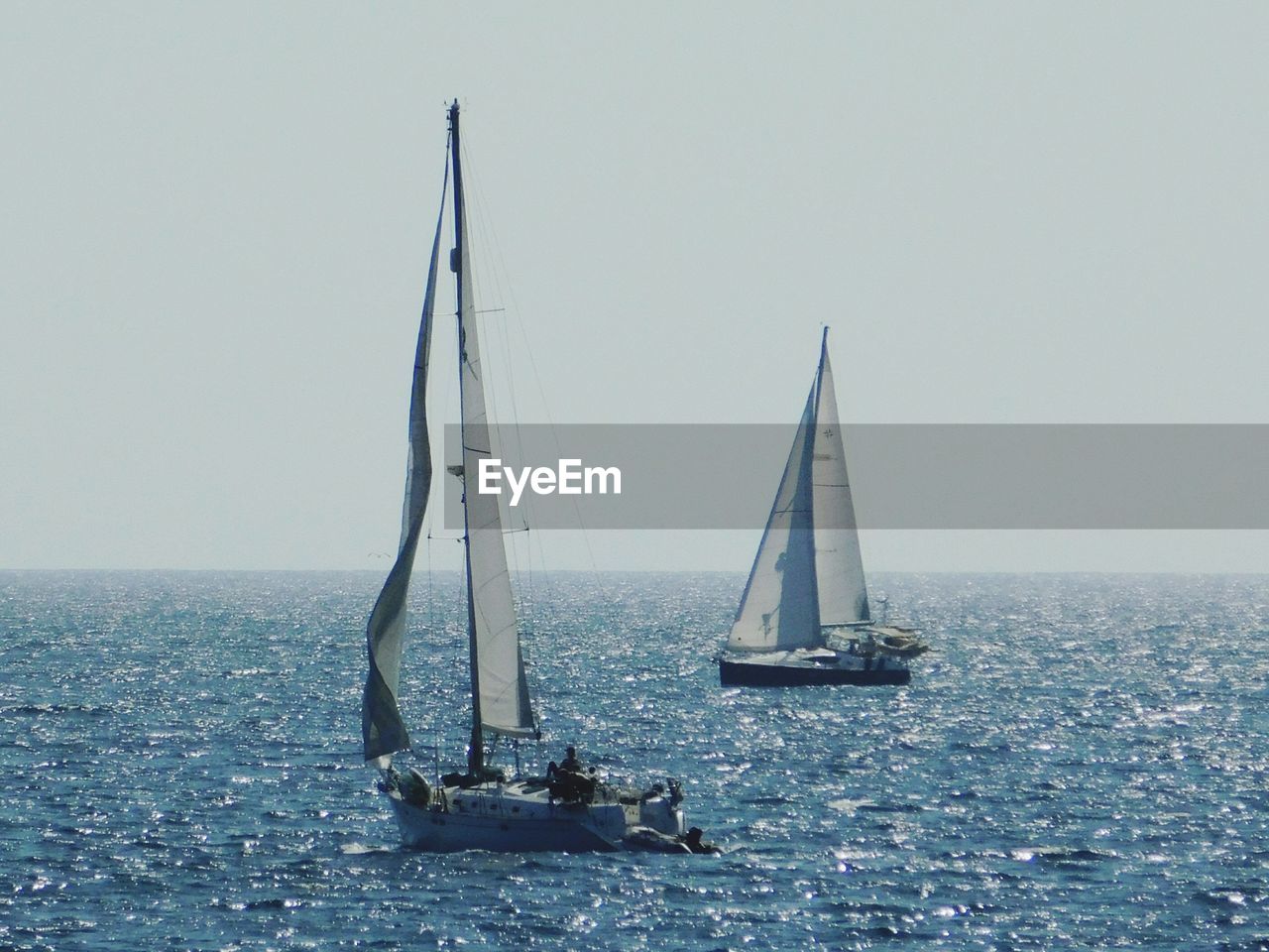 SAILBOATS SAILING IN SEA AGAINST CLEAR SKY