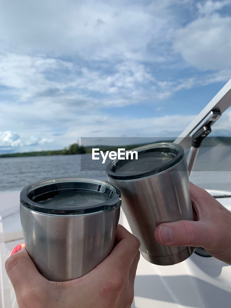 CROPPED IMAGE OF PERSON HOLDING DRINK AGAINST SKY