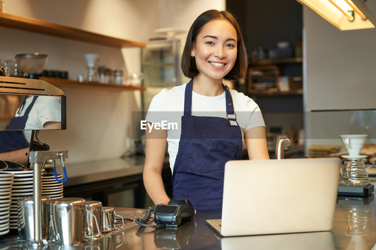 portrait of young woman using mobile phone while sitting on table