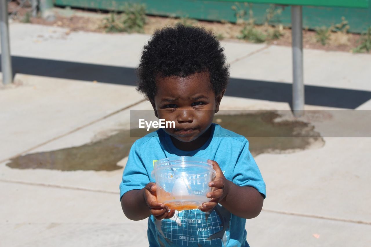 Portrait of cute boy drinking juice outdoors