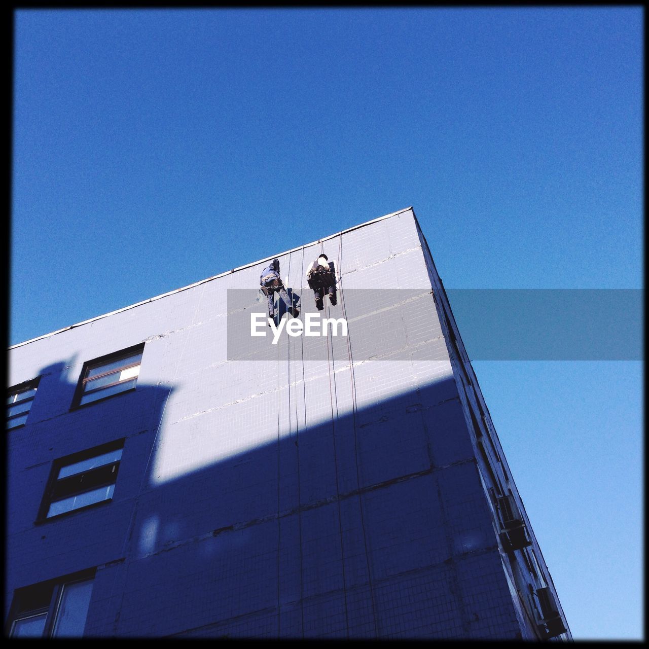 Low angle view of men painting skyscraper