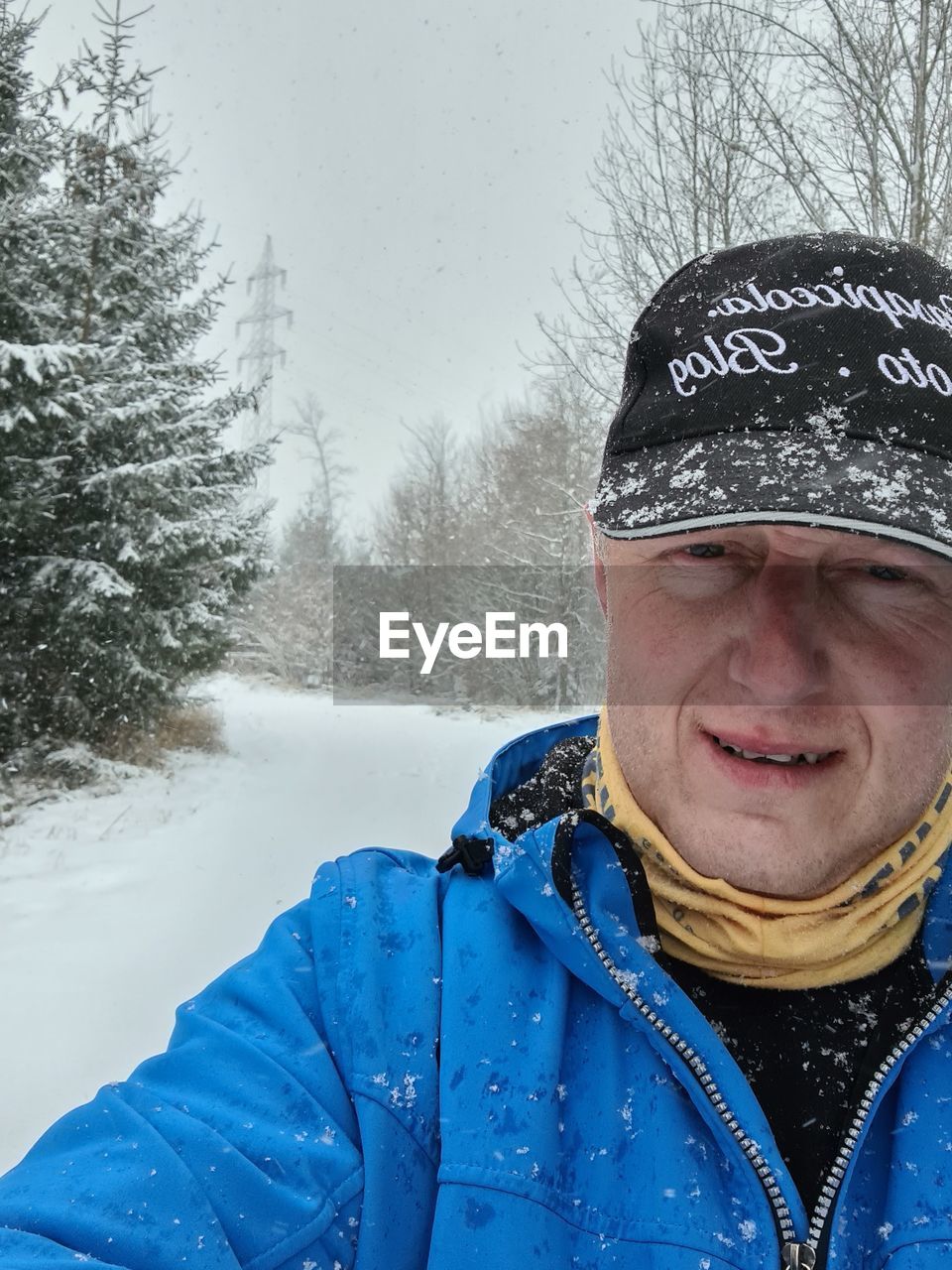 PORTRAIT OF MAN IN SNOW AGAINST TREES