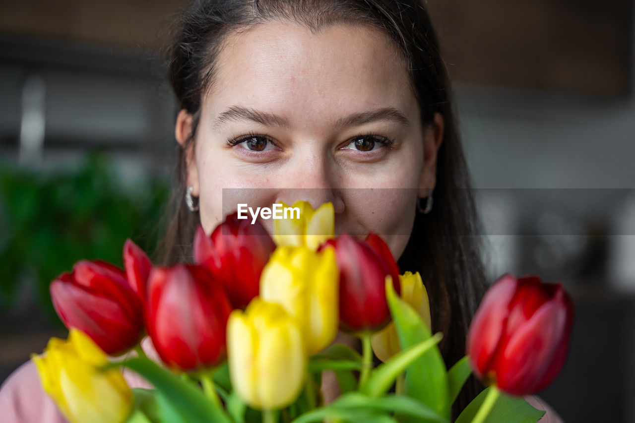 close-up portrait of young woman with red flowers