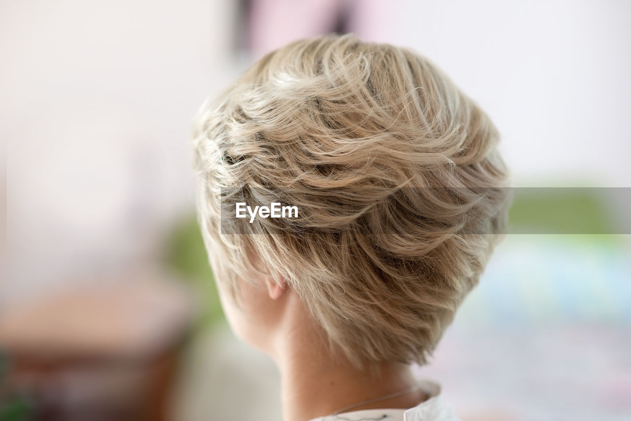 Rear view of woman with blond short hair at home