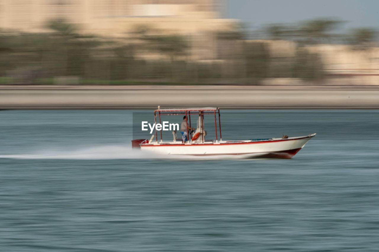 Blurred motion on man riding motorboat on sea