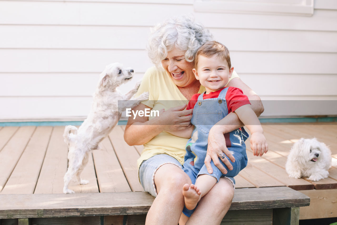 Senior woman and boy with dogs sitting outdoors