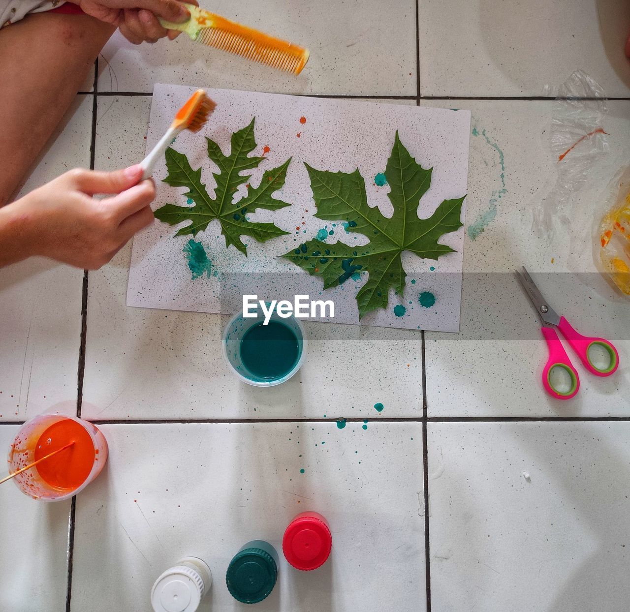 Kids playing and coloring with leaf on the floor.