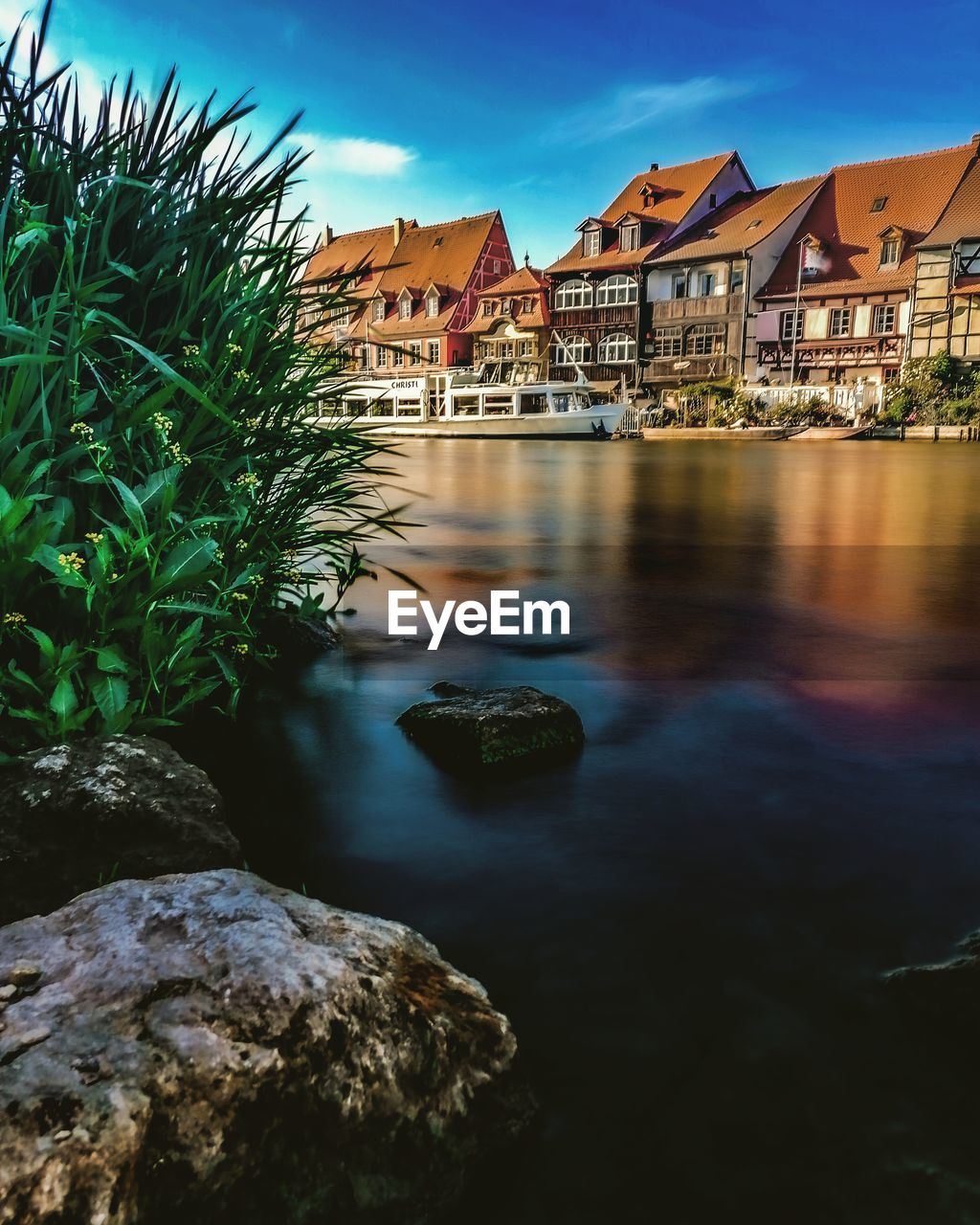 River amidst houses and buildings against sky