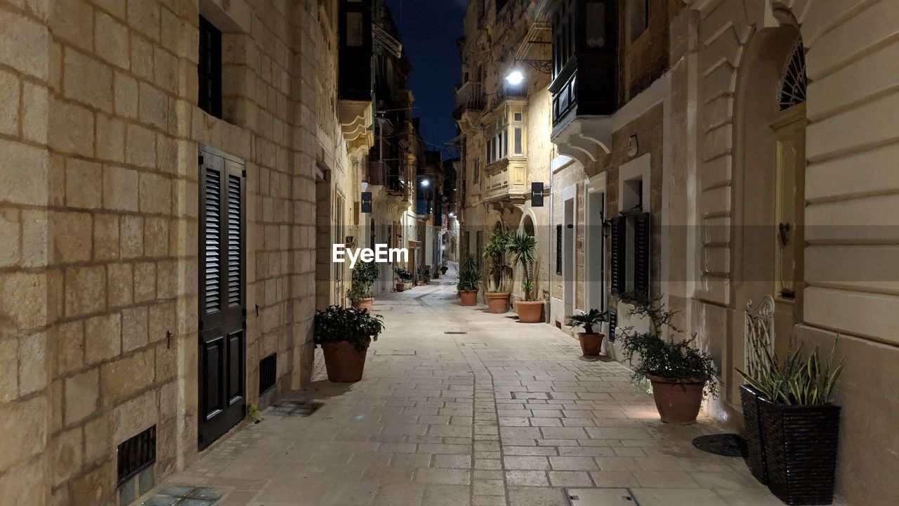 Narrow alley amidst buildings in city at night