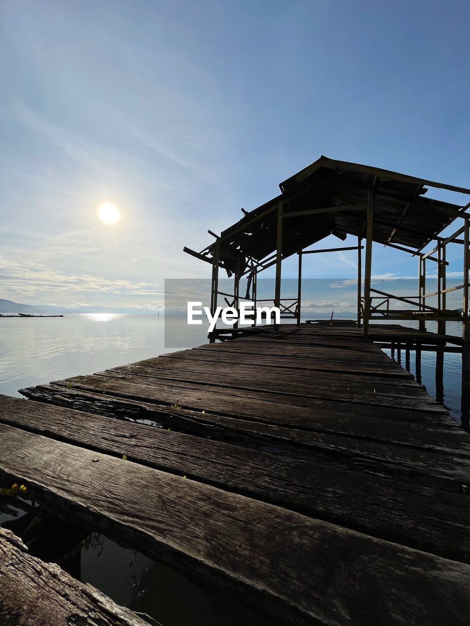 sky, architecture, water, sea, built structure, ocean, nature, pier, coast, wood, reflection, horizon, sunlight, beach, sunset, tranquility, no people, scenics - nature, sun, beauty in nature, land, outdoors, hut, cloud, evening, boardwalk, tranquil scene, building exterior, walkway, blue, jetty, dusk, shore, day, travel destinations, horizon over water, environment