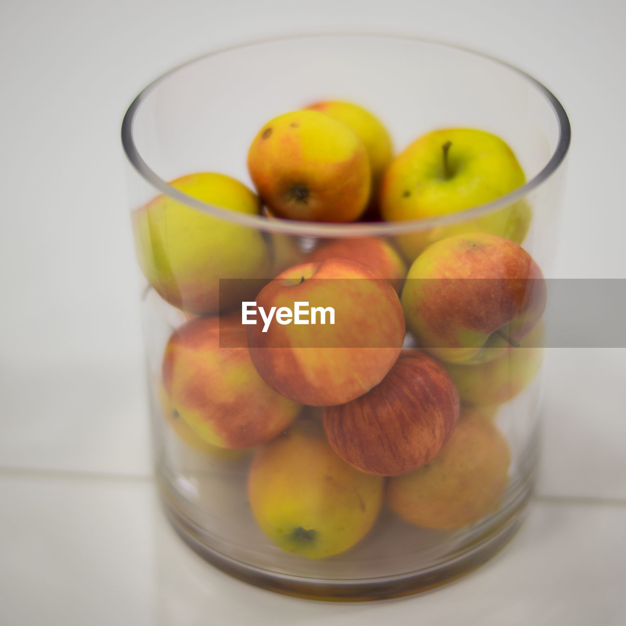 Close-up of apples in glass container on white background