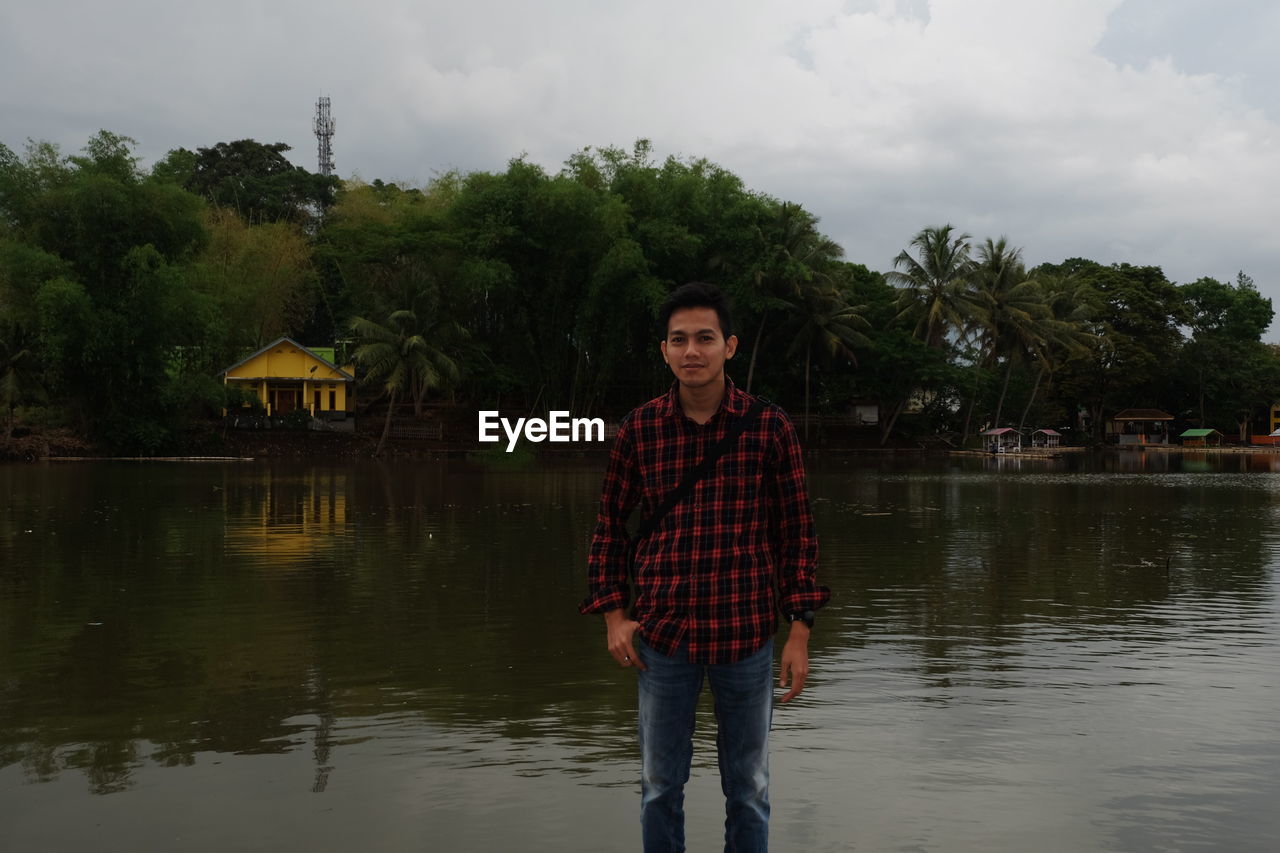 Portrait of man standing in lake against sky