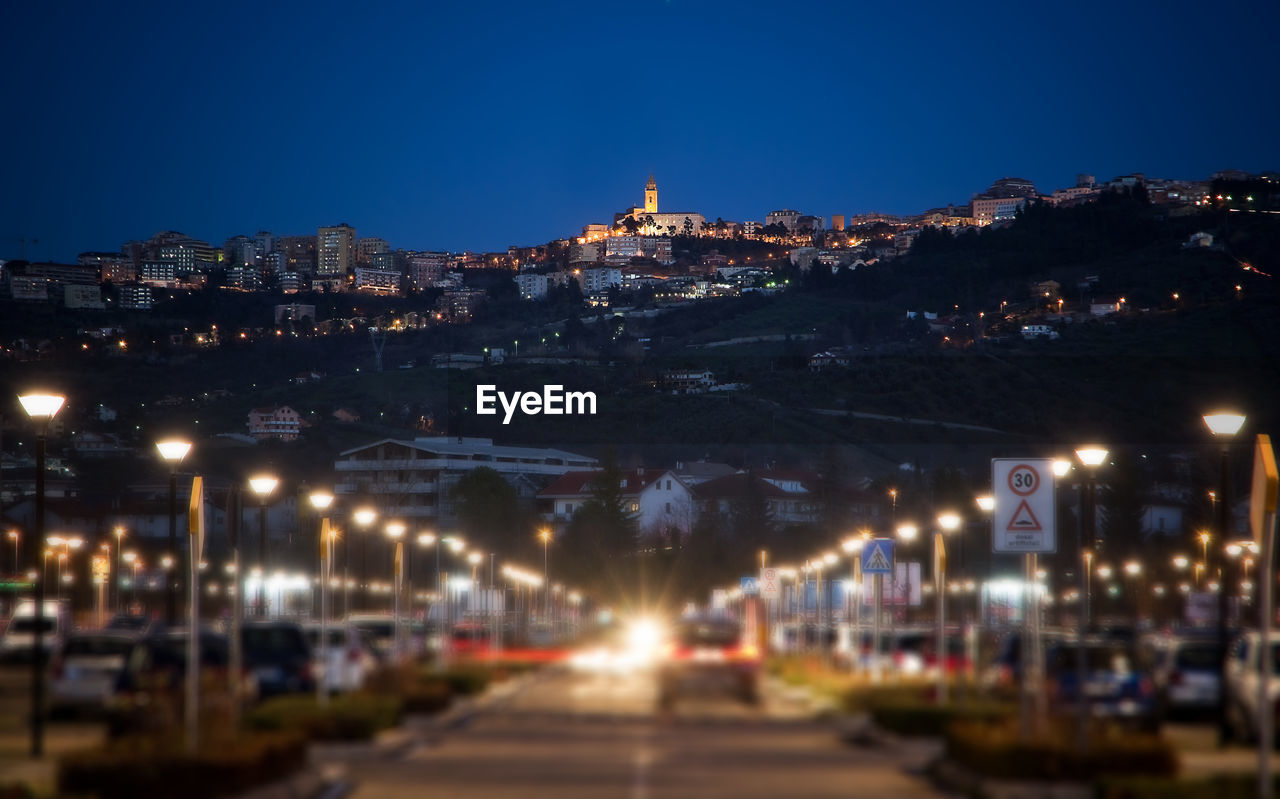 ILLUMINATED CITY AGAINST CLEAR BLUE SKY