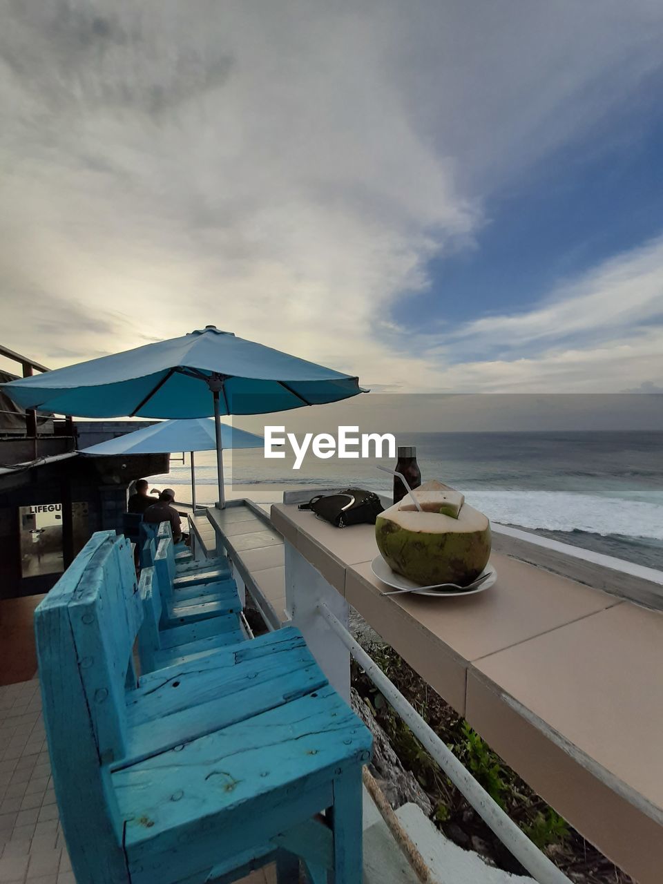 Chairs by swimming pool on beach against sky