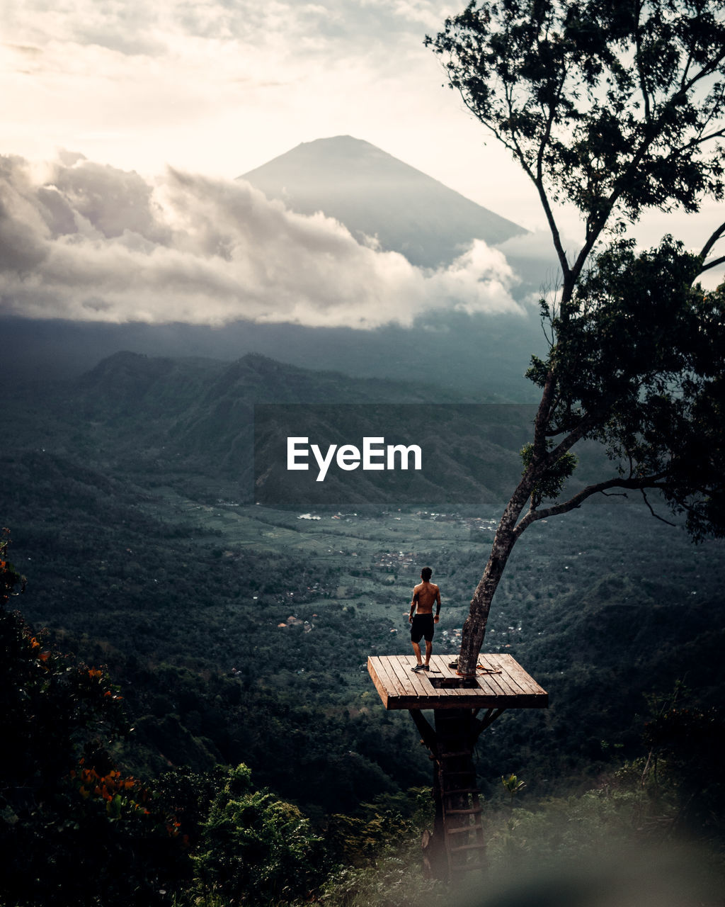 Man sitting on mountain against sky