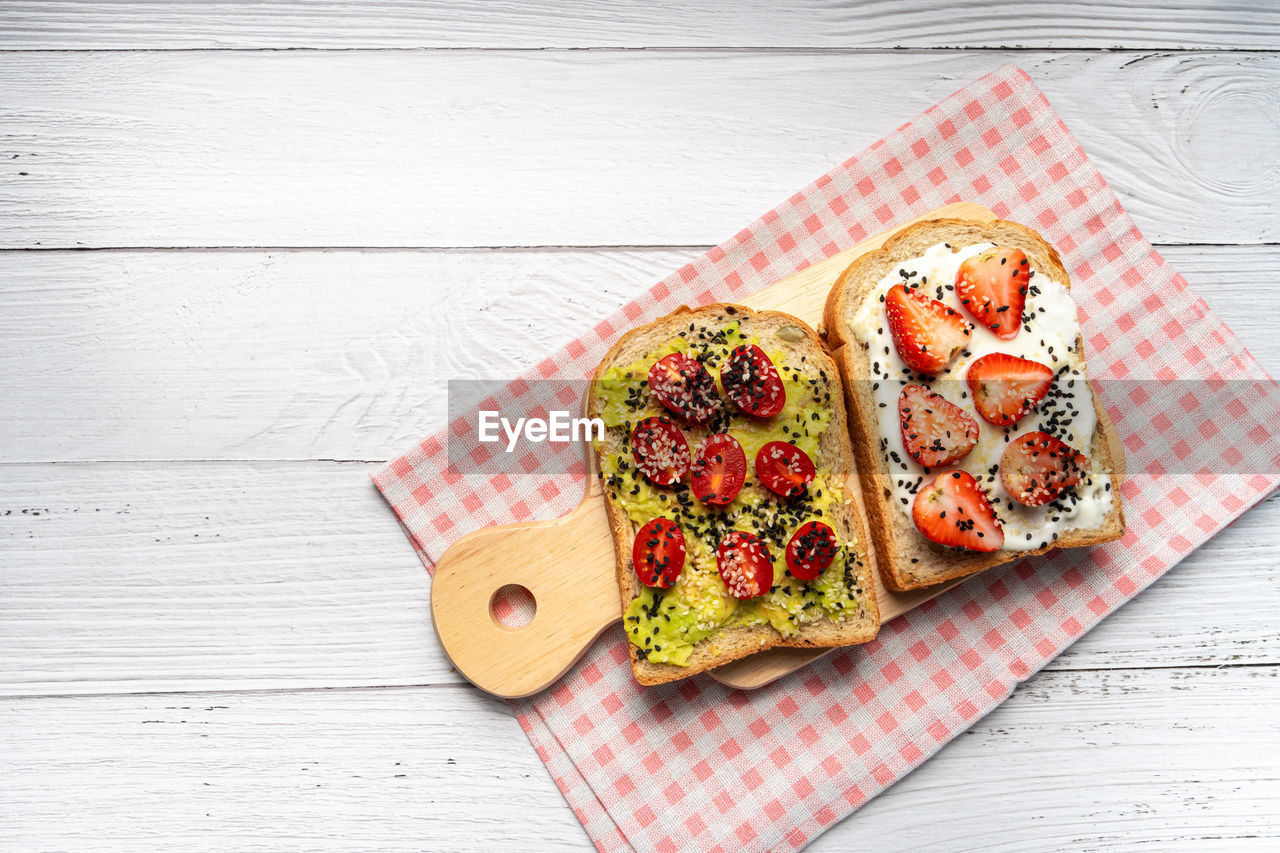 Healthy breakfast toasts with avocado toast, tomato, strawberry, yoghurt
