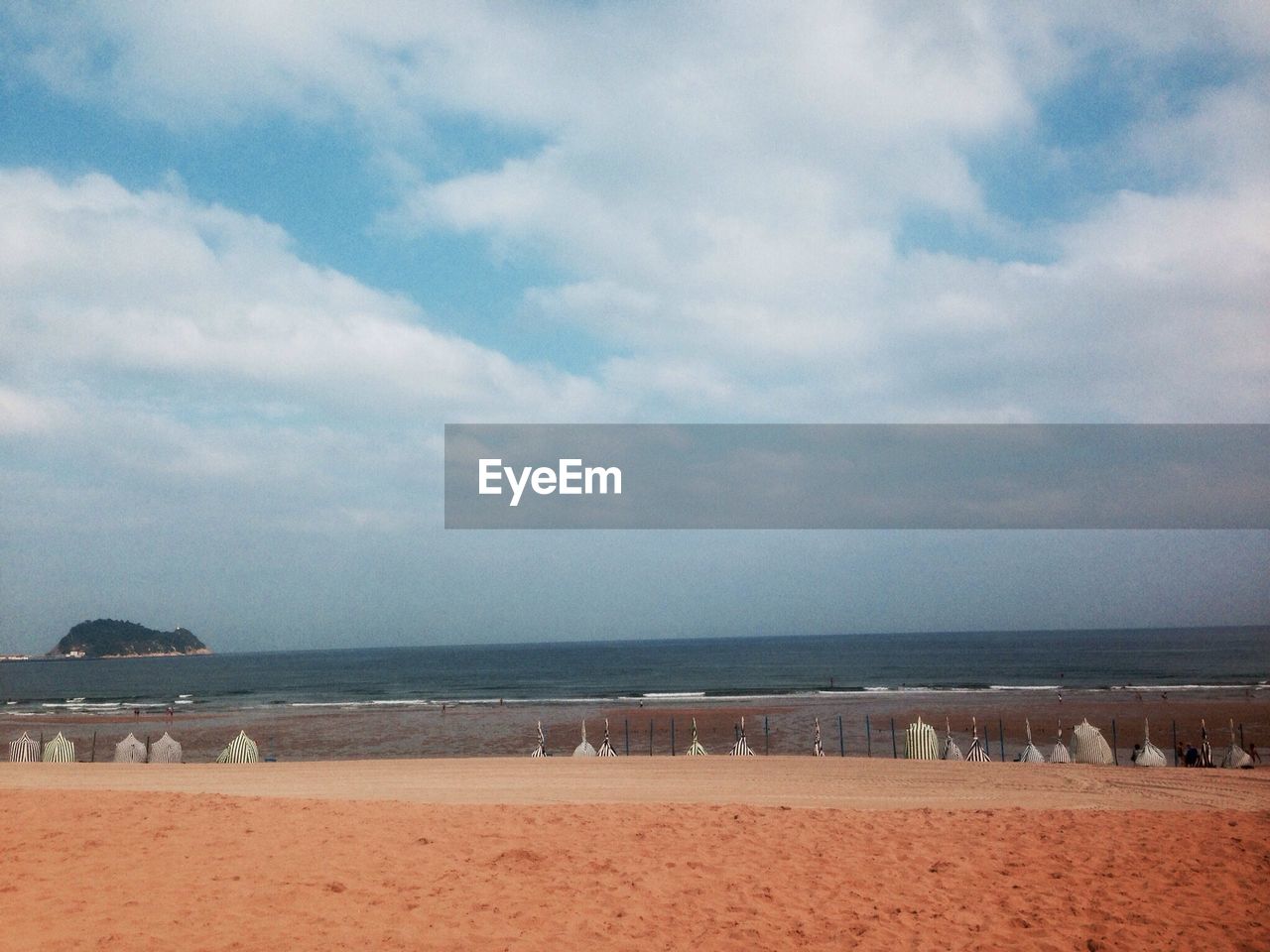 Scenic view of beach by sea against cloudy sky