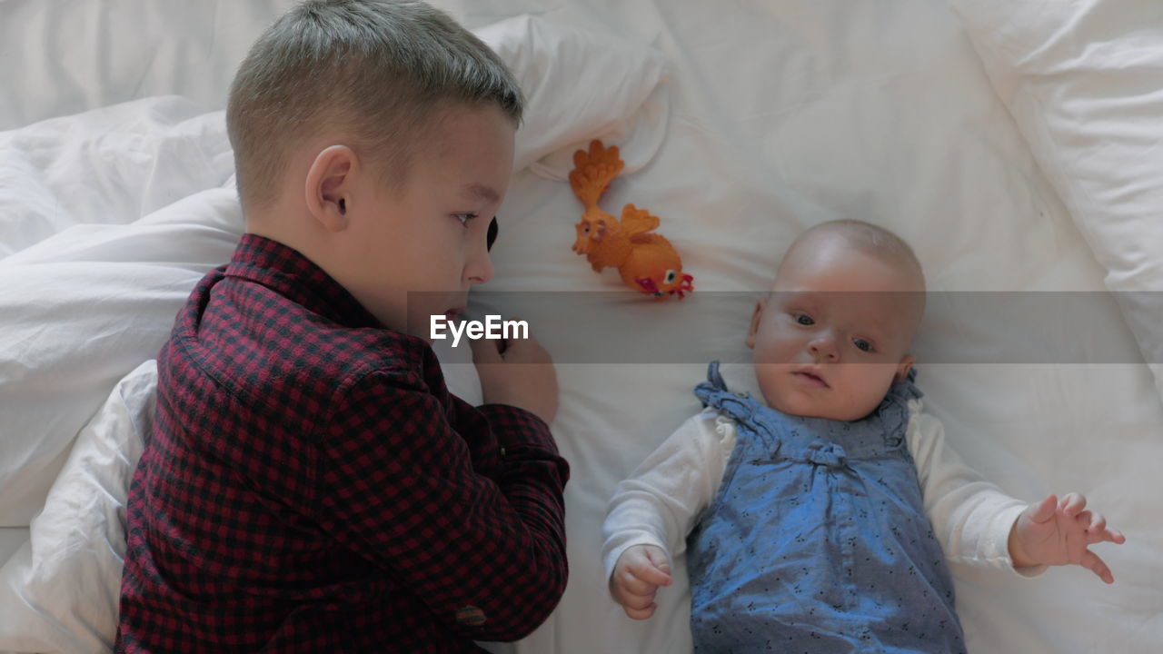 HIGH ANGLE VIEW OF CUTE BABY BOY ON BED