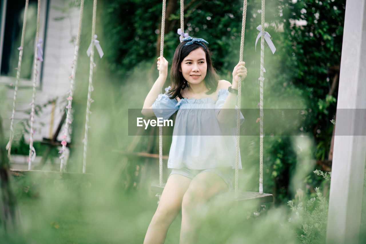 Woman sitting on swing at park