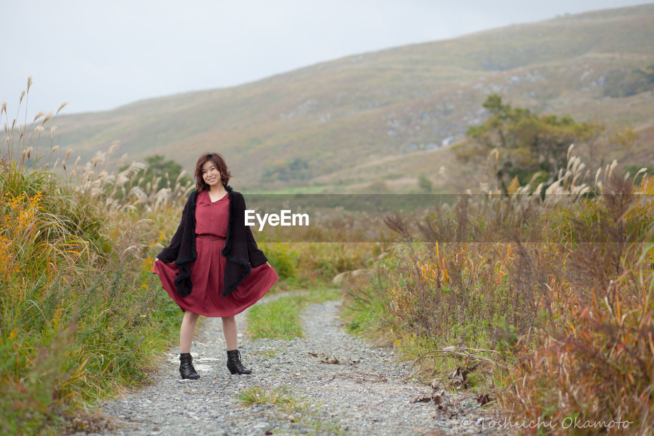 PORTRAIT OF YOUNG WOMAN ON GRASSLAND