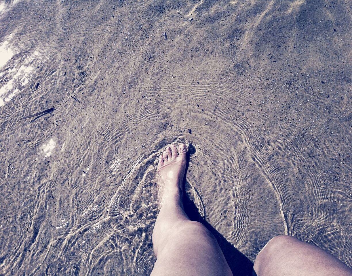 Close-up of barefoot in shallow water