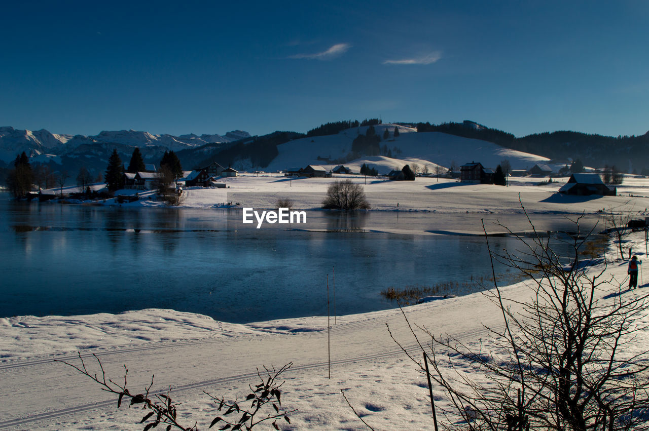 Scenic view of frozen lake by mountains against sky