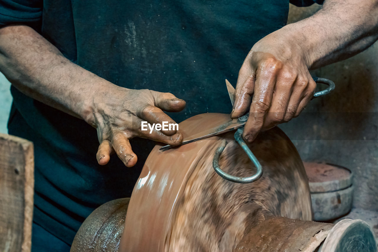 Close-up of a person sharpening scissors on a stone wheel