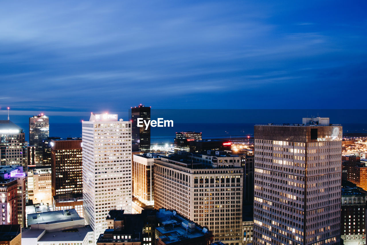 Illuminated cityscape against blue sky