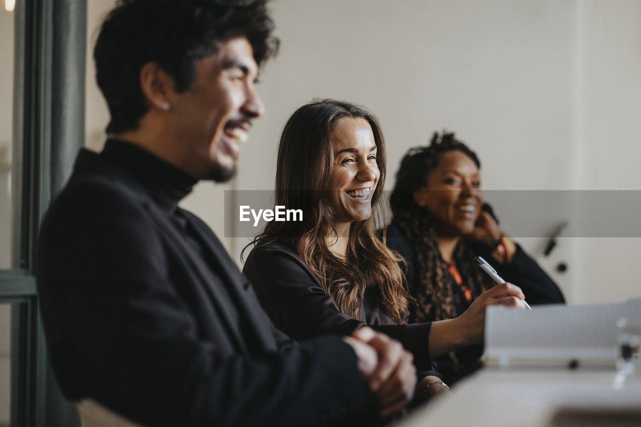 Happy male and female business colleagues during meeting in board room at office