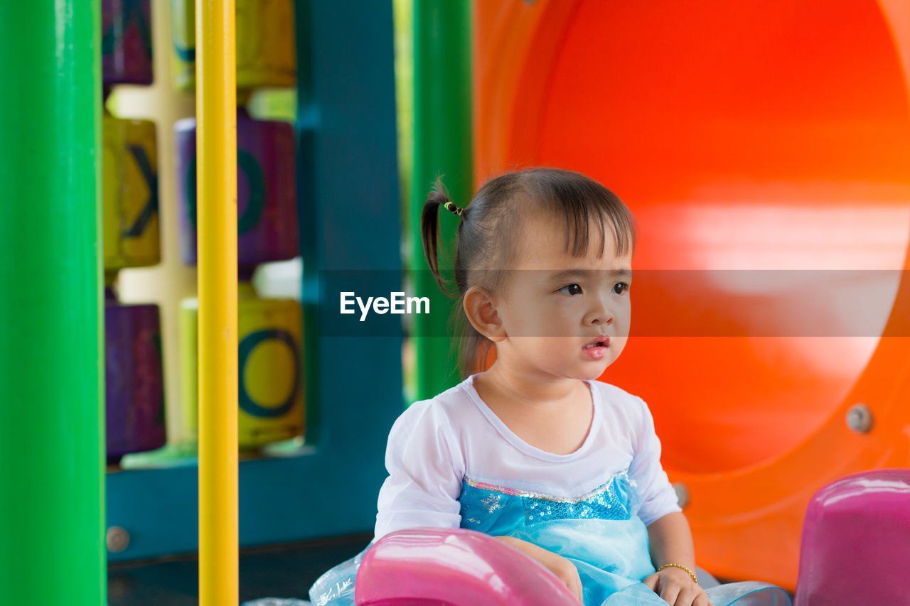 Cute girl sitting by tunnel at playground