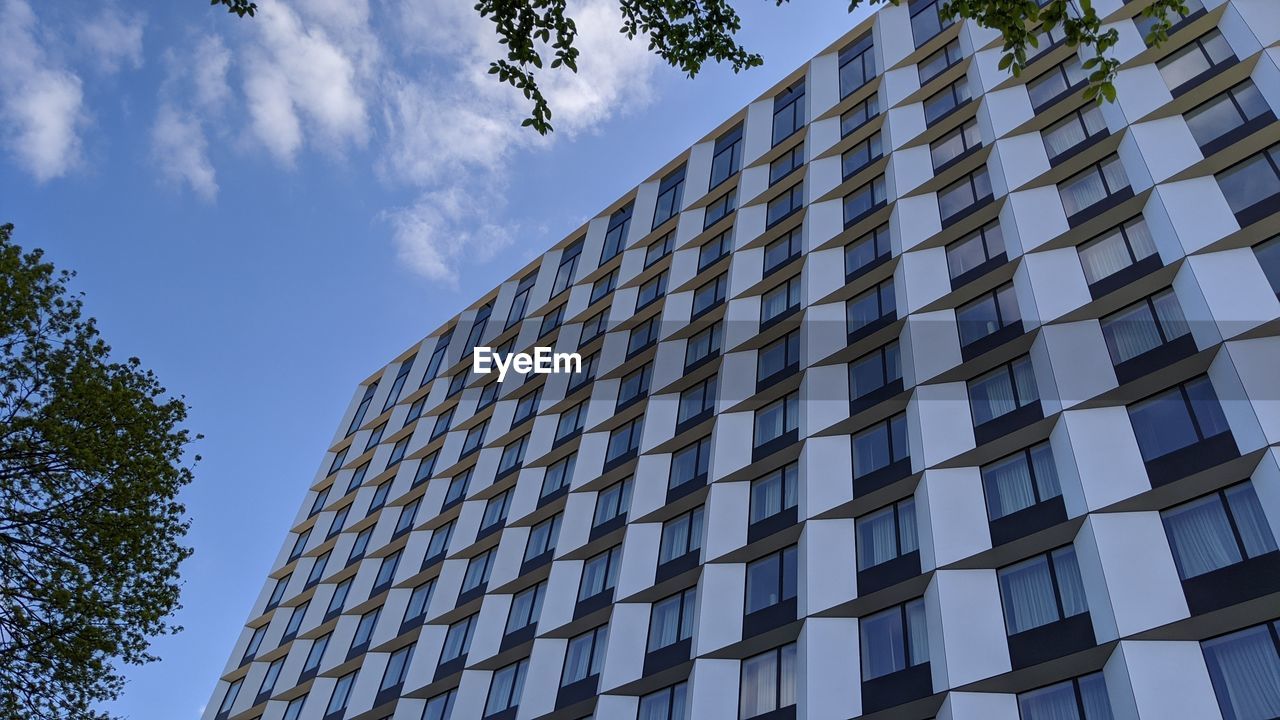 LOW ANGLE VIEW OF MODERN GLASS BUILDING AGAINST SKY