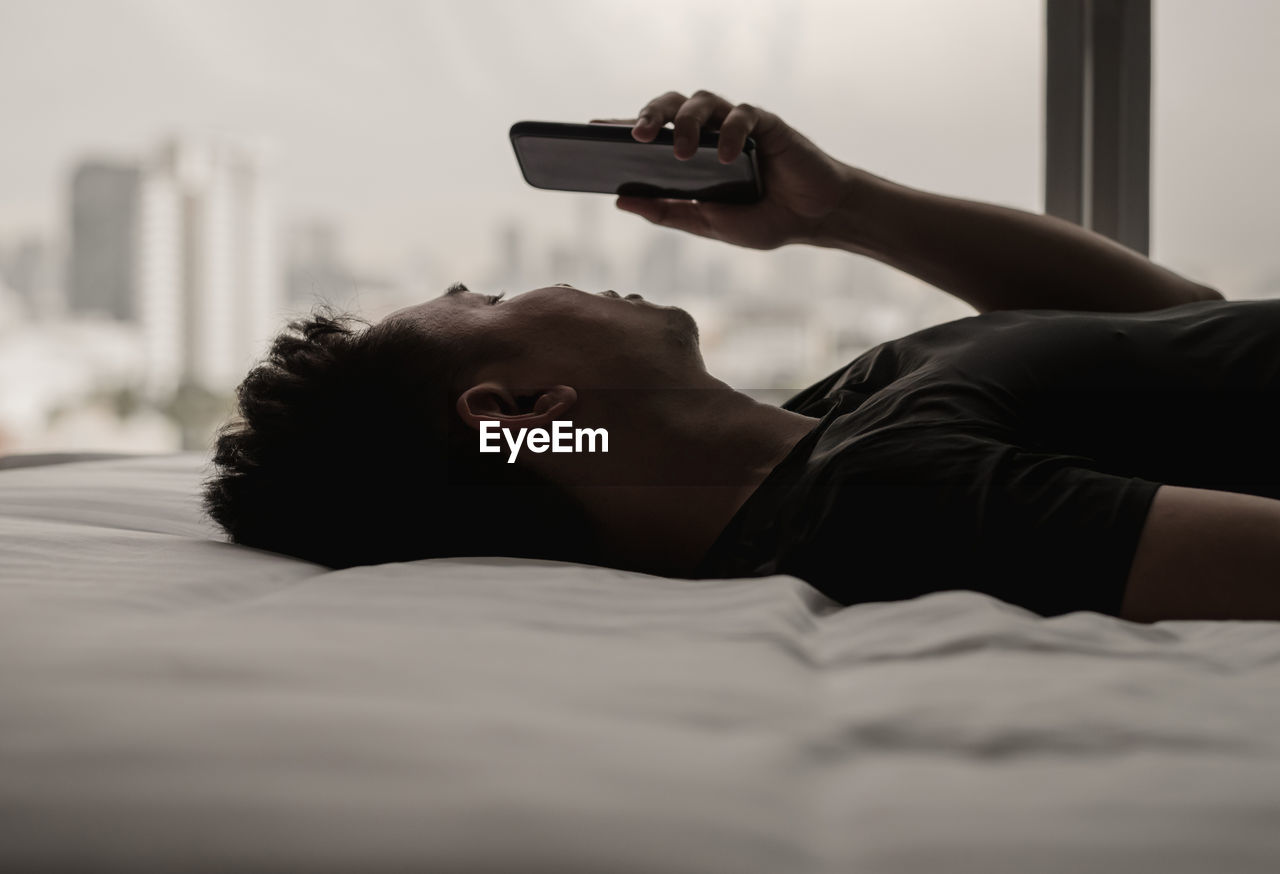 Asian man feels sad on bed looking and focus on smartphone. mental health concept.