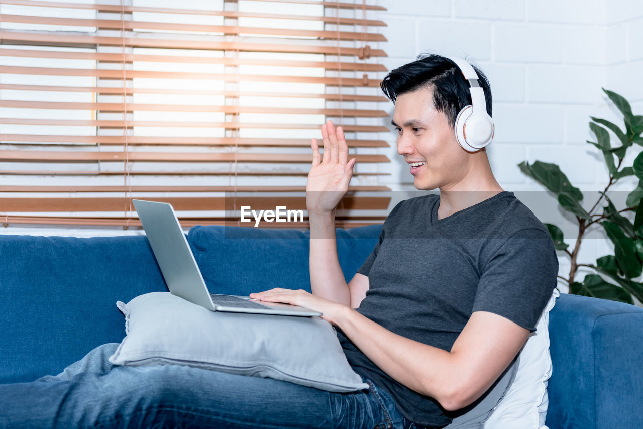 YOUNG MAN USING MOBILE PHONE WHILE SITTING AT OFFICE