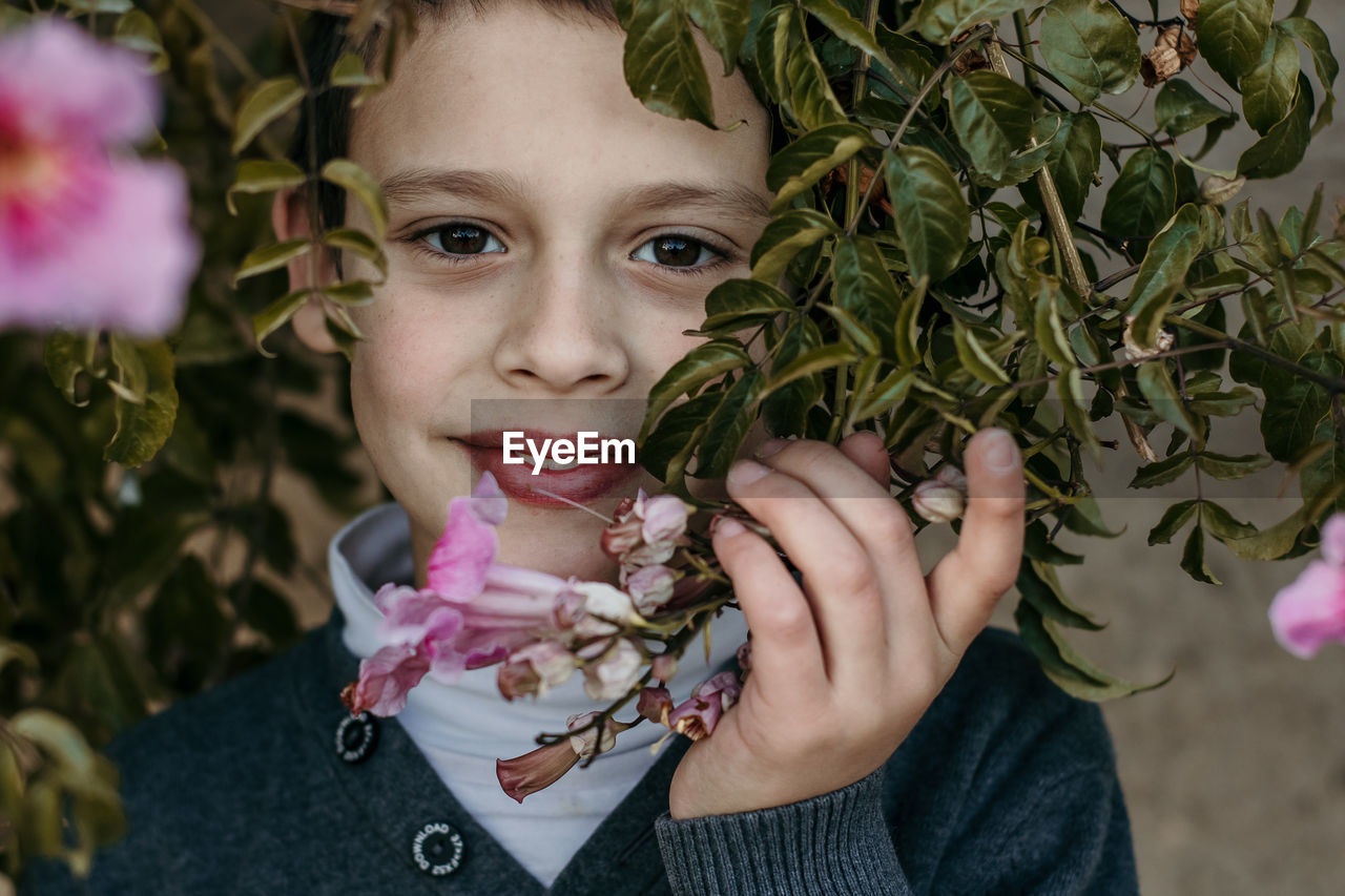 Portrait of smiling boy holding plant outdoors