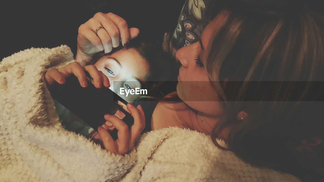 Girl using mobile phone with mother at home