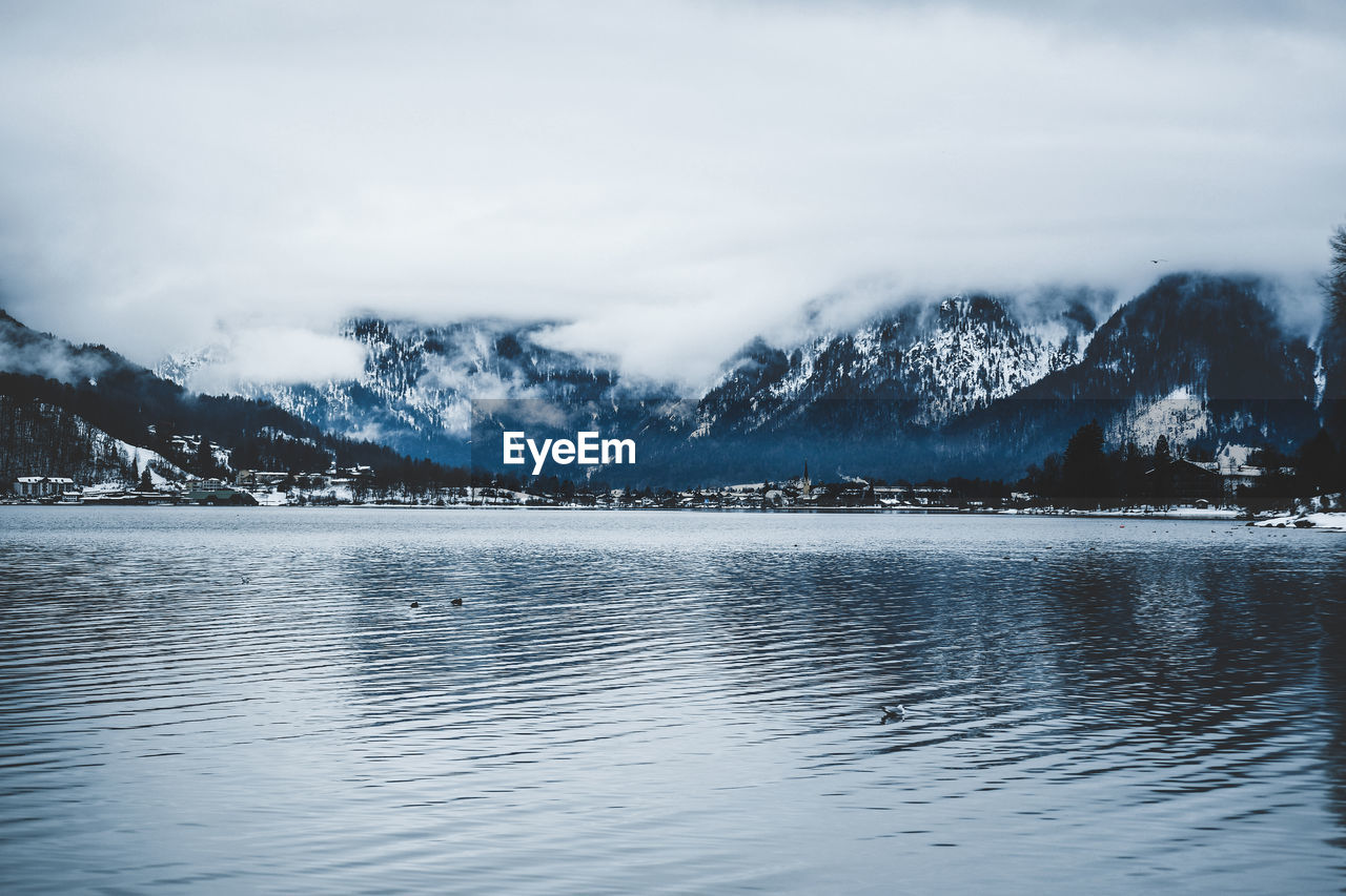 Scenic view of lake by snowcapped mountains against sky