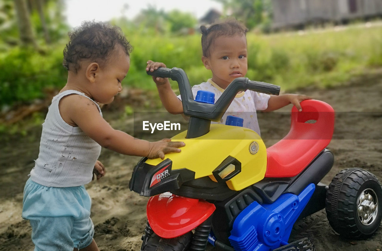 childhood, child, men, vehicle, toddler, baby, two people, fun, transportation, togetherness, toy, emotion, playground, land vehicle, happiness, person, leisure activity, family, nature, full length, mode of transportation, smiling, day, wheel, car, lifestyles, casual clothing, learning, female, cute, outdoors, sports, friendship, positive emotion, enjoyment, tree, education, innocence, motor vehicle