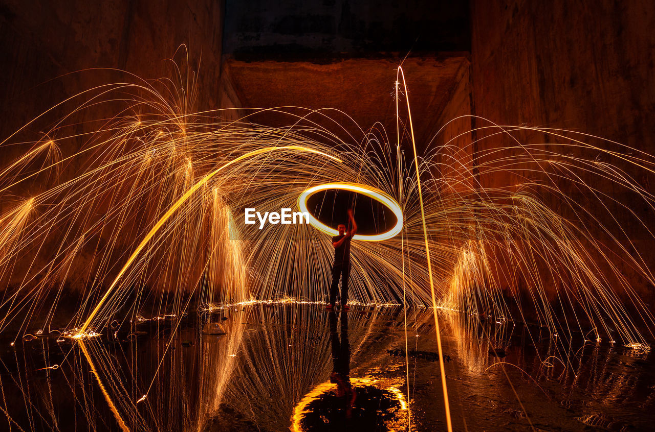 Man spinning wire wool while standing on street at night