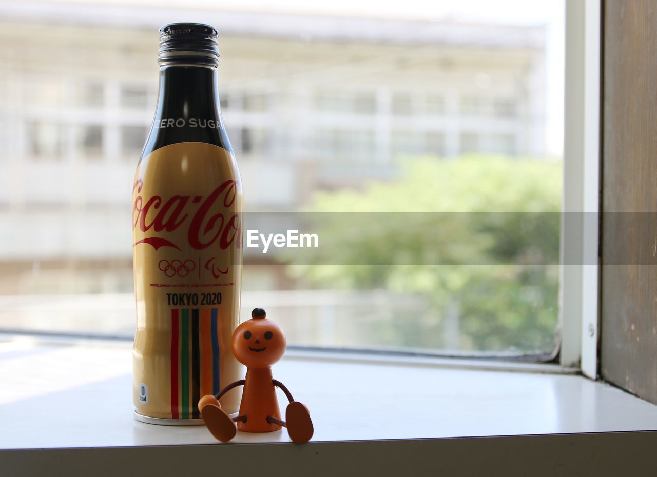 CLOSE-UP OF BOTTLE ON TABLE AGAINST WINDOW