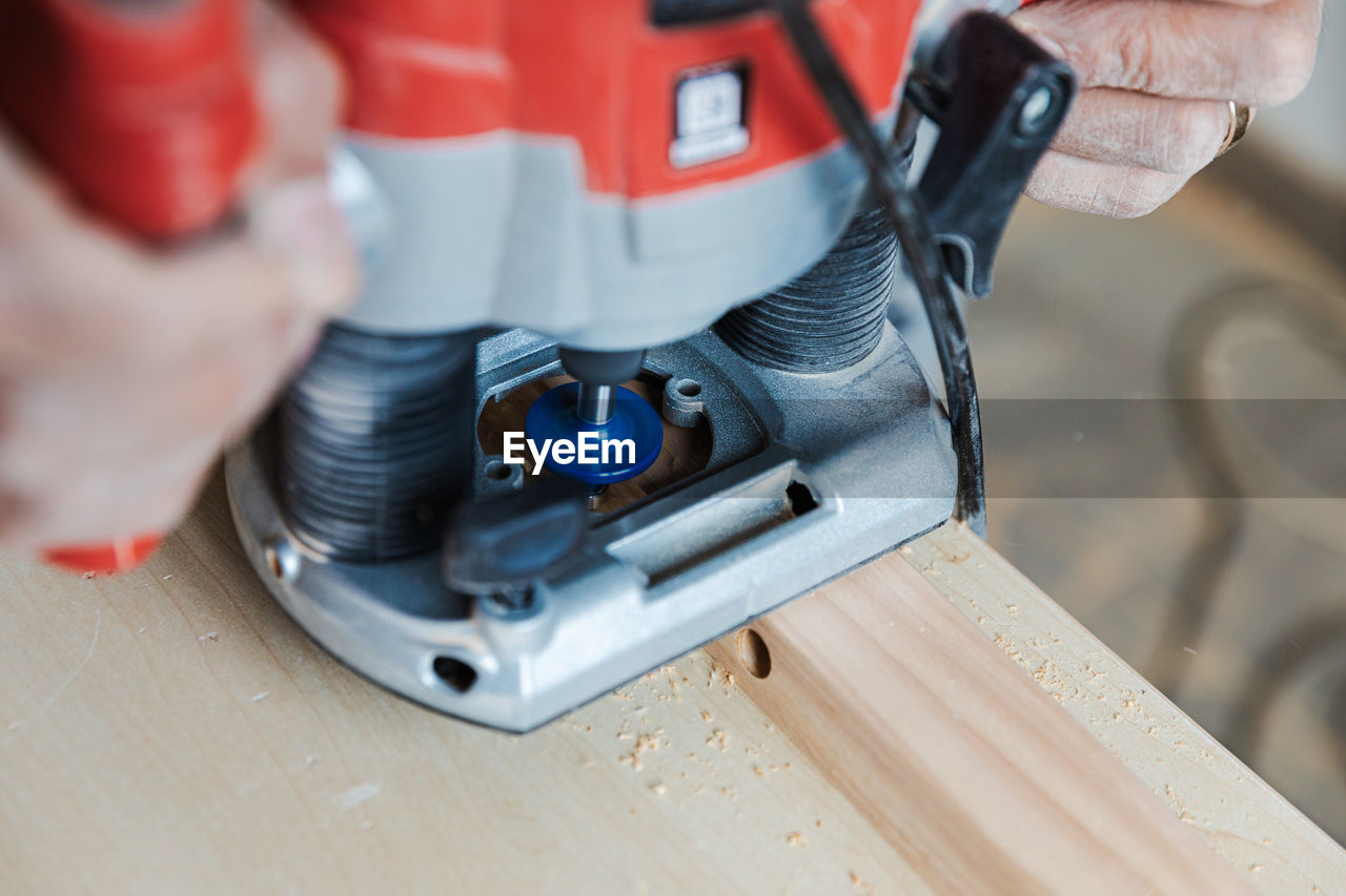 Carpenters hands hold an electric planer woodwork close view
