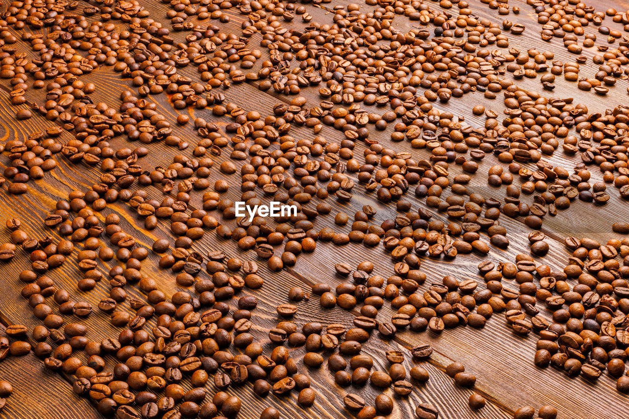 Roasted coffe beans spreaded over wooden board - full frame background