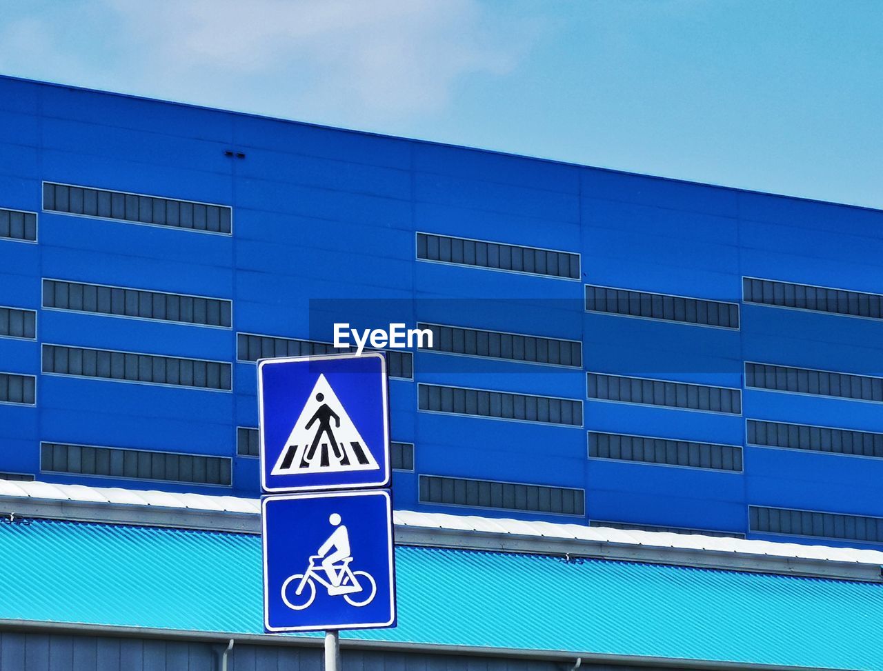 Low angle view of blue building against clear sky and road sign