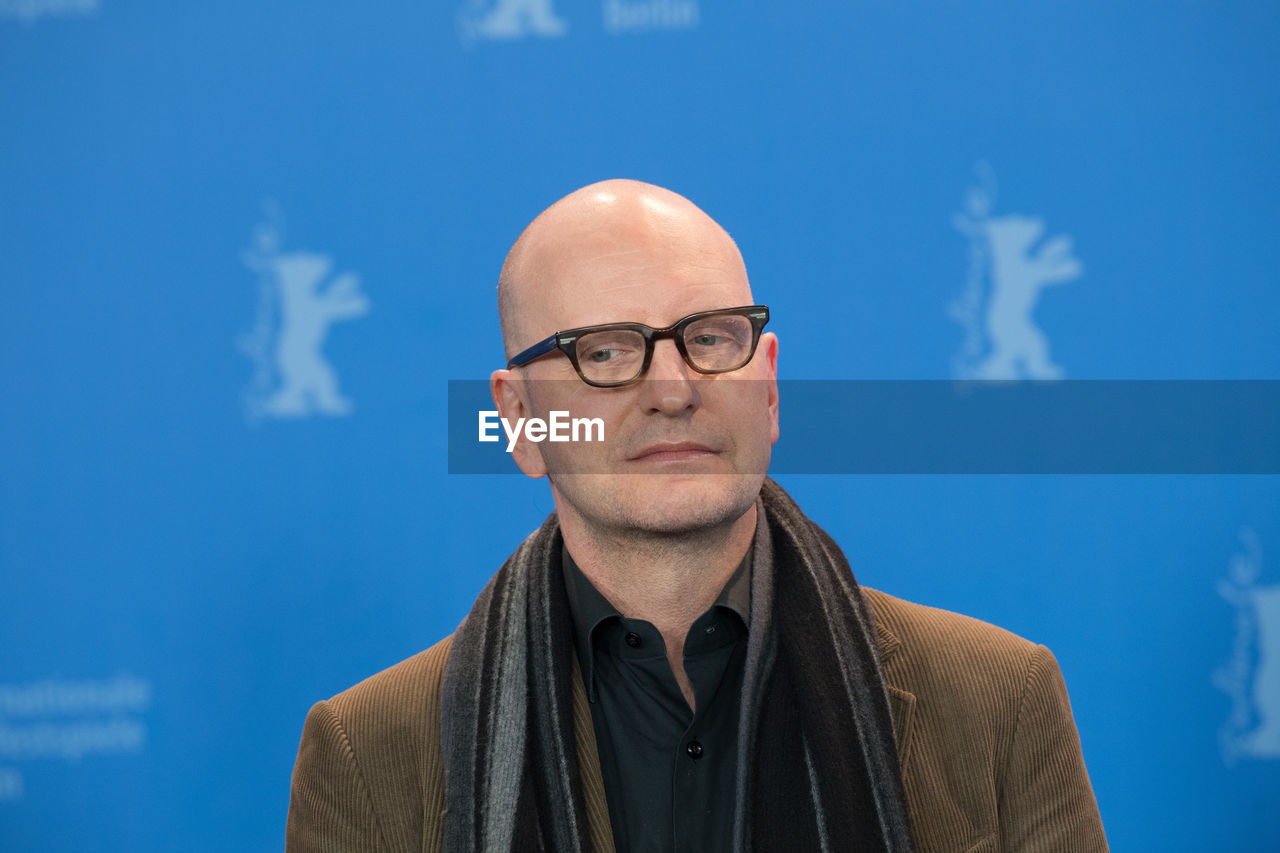 CLOSE-UP PORTRAIT OF MAN WEARING EYEGLASSES AGAINST BLUE SKY