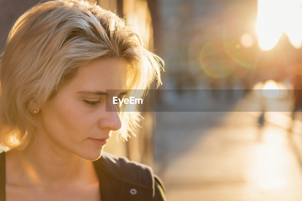 Young blond woman portrait in sunset light outdoor on a city street