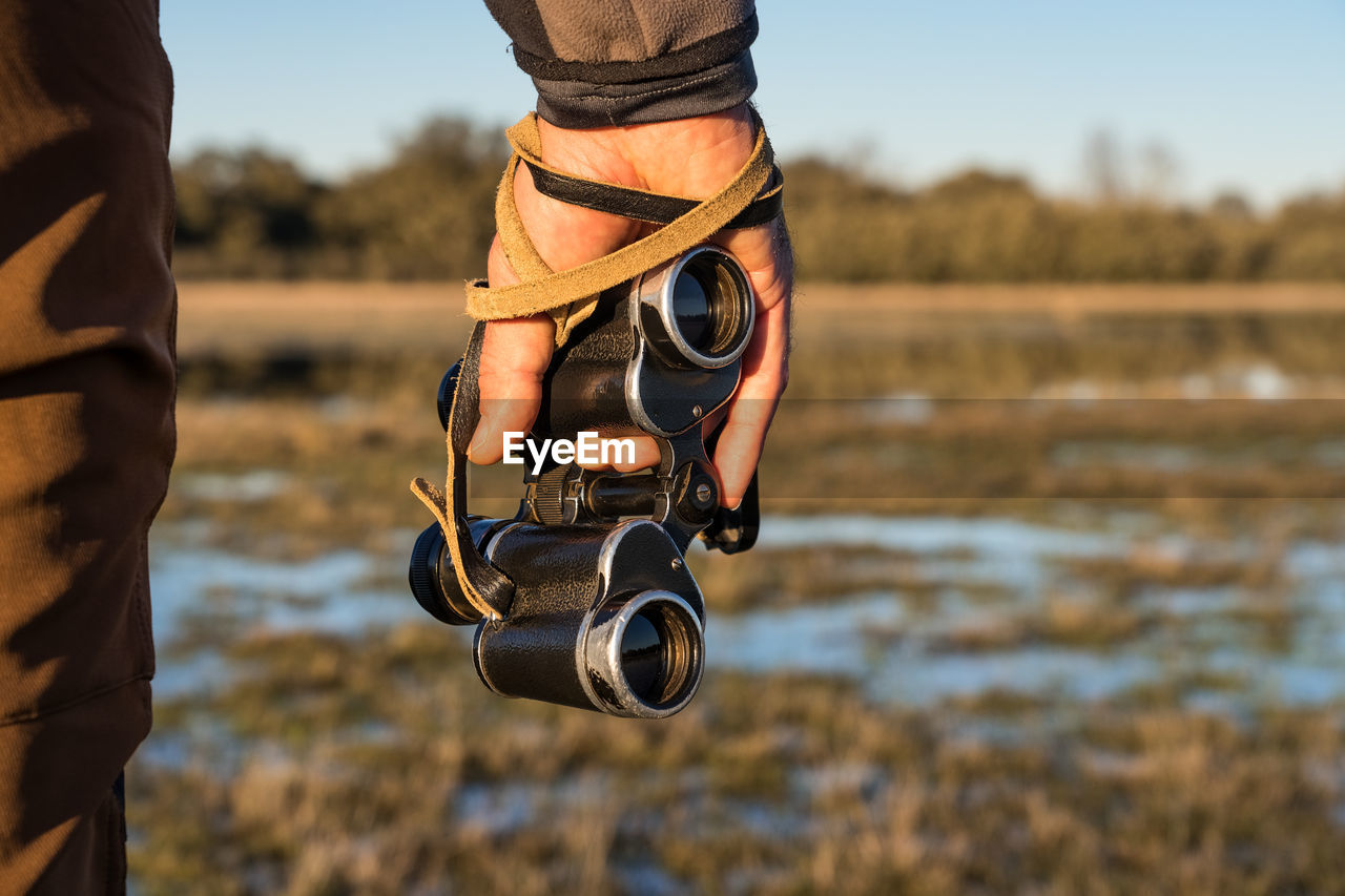 Cropped unrecognizable man looking through an old binoculars the fauna of a lagoon in spain