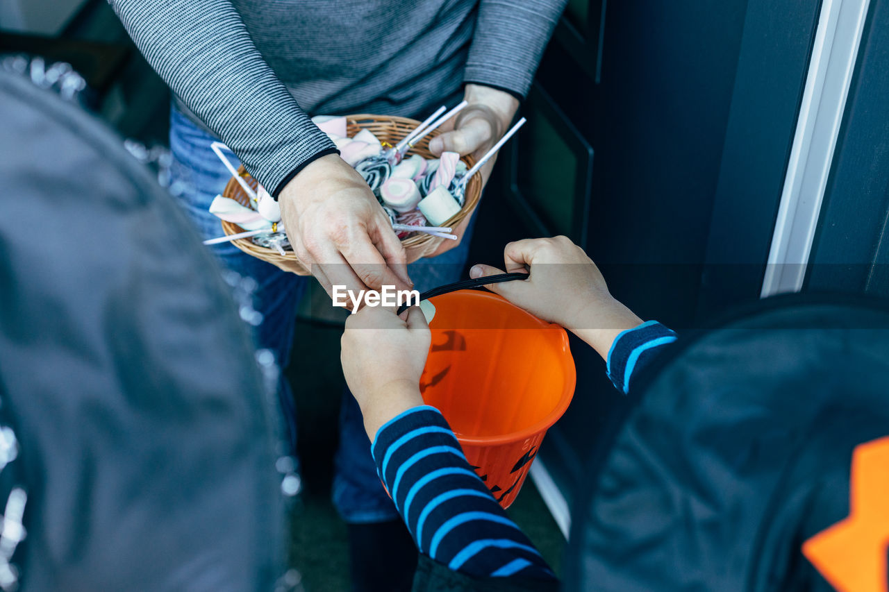 Close-up of a man handing out sweets to children on halloween. kids tricks or treats