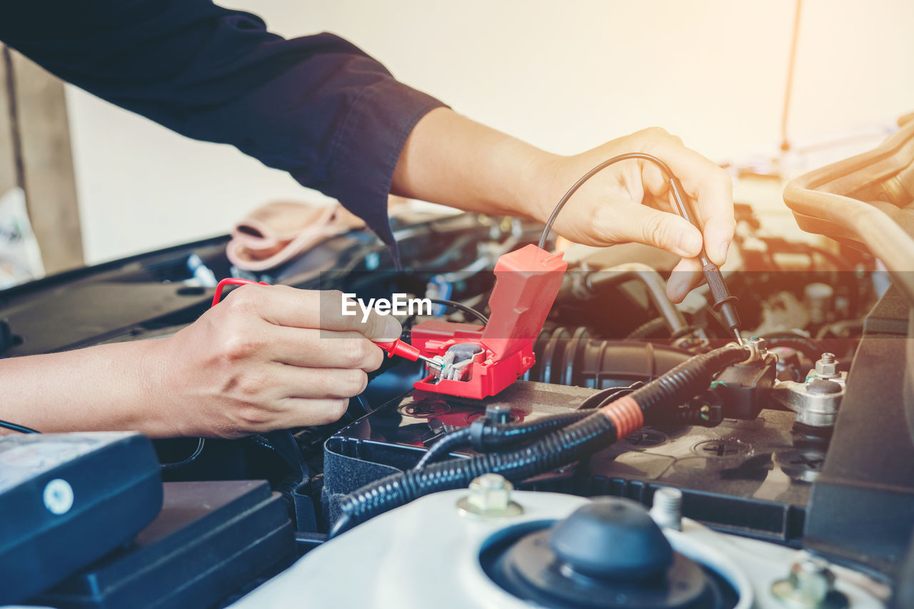 Cropped hands of mechanic repairing car in garage