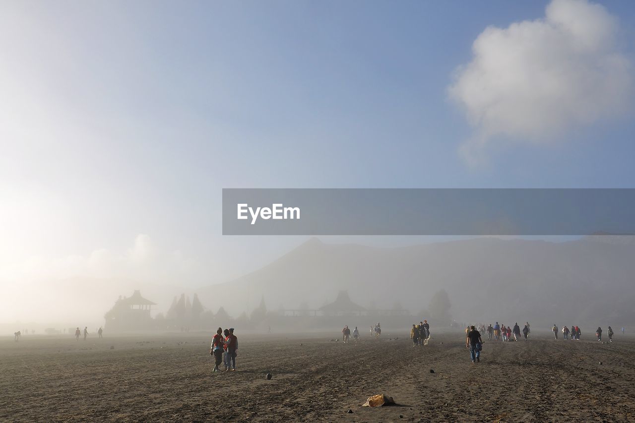 People on field against sky during foggy weather