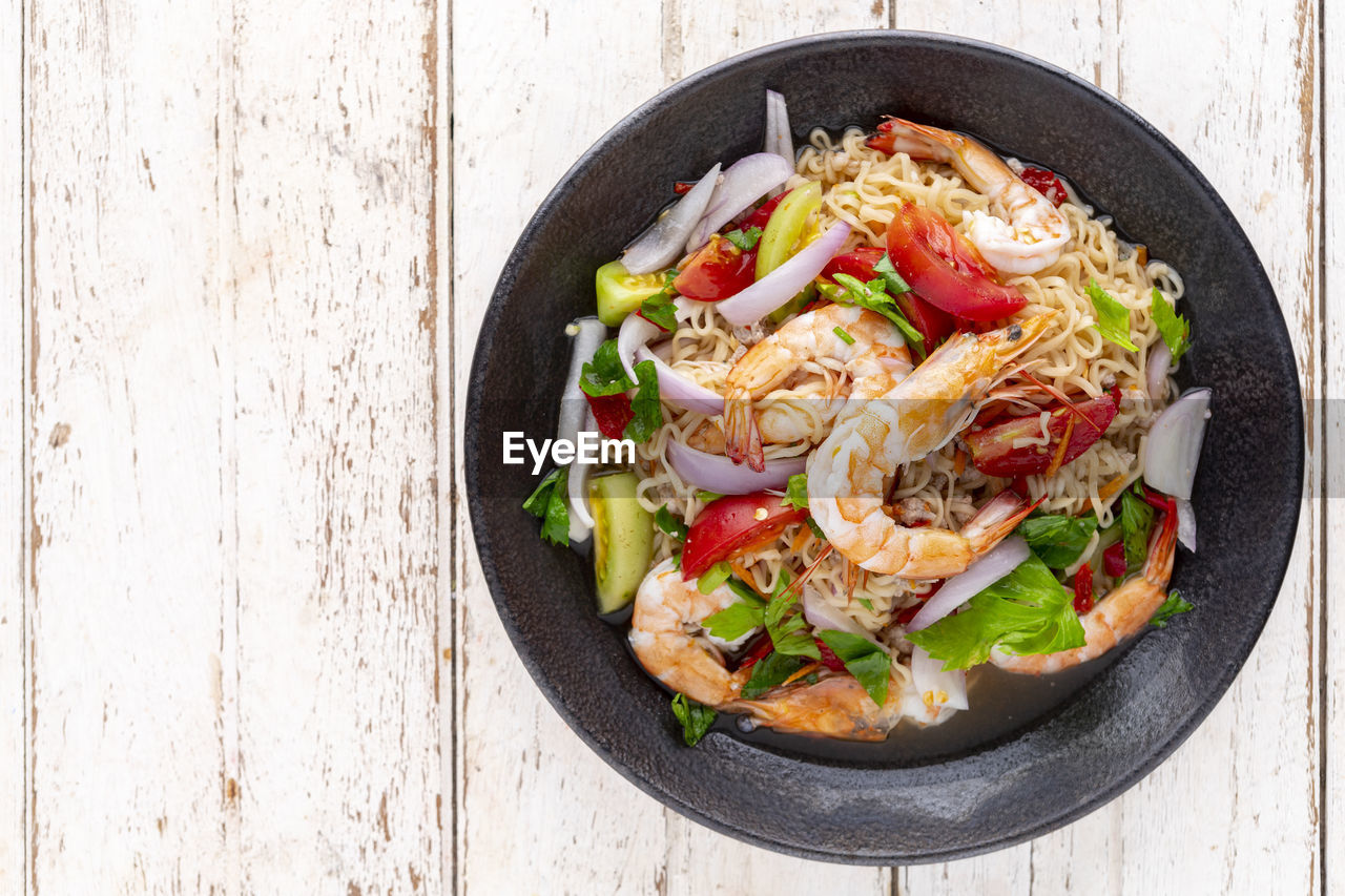 Spicy and sour instant noodle salad with shrimp, pork, tomato, lime, red onion, shallot and celery