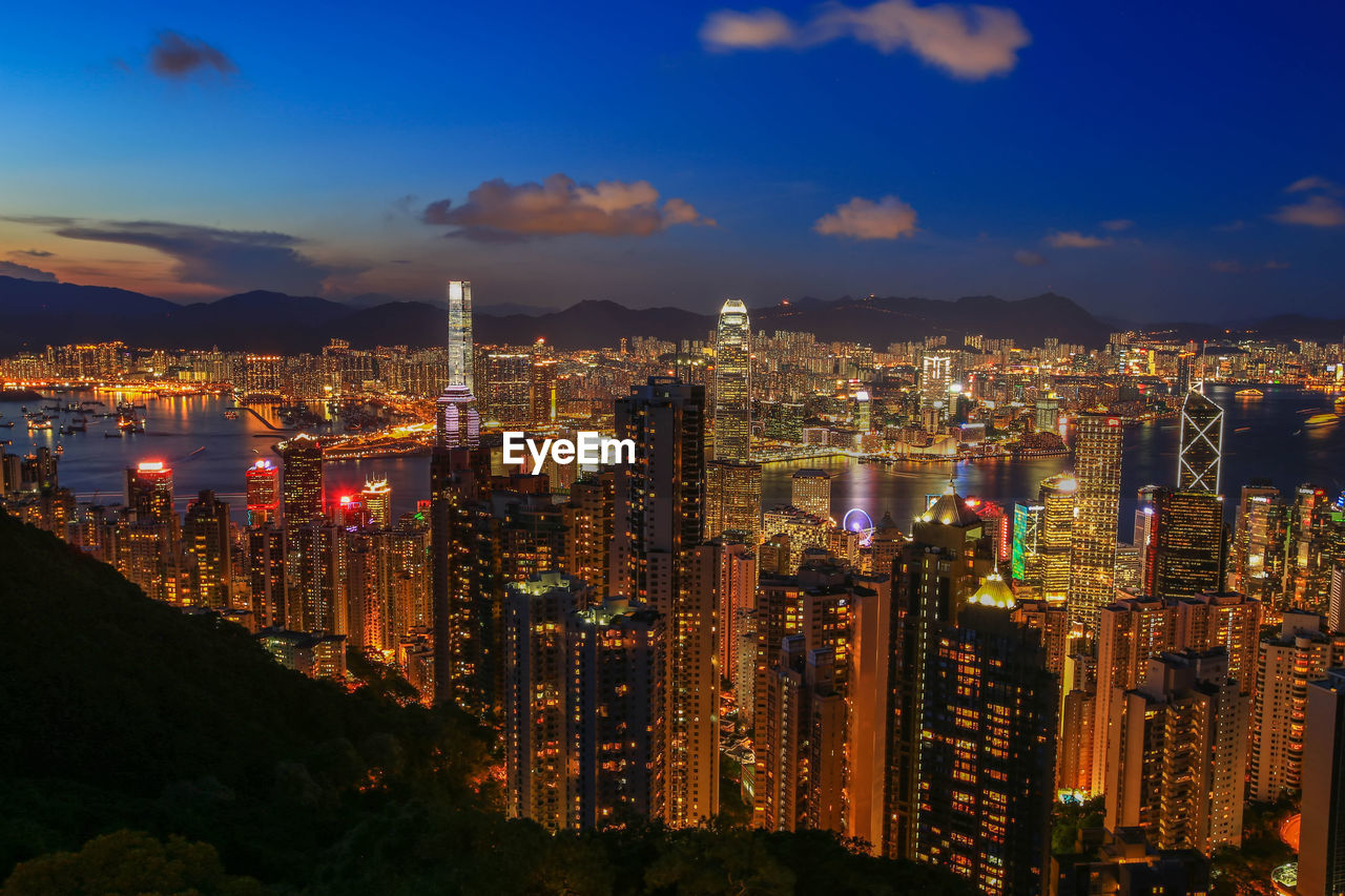 Illuminated modern buildings in city against sky